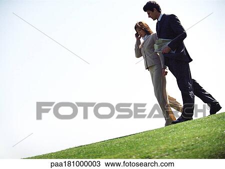 Businessman and woman with cell phone, walking on grass View Large Photo Image Stock Image - Businessman and woman with cell phone, walking on grass. Fotosearch