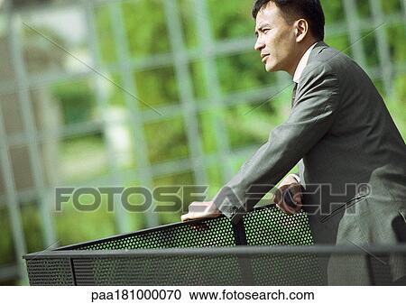 Businessman leaning on railing, close-up View Large Photo Image Stock Image - Businessman leaning on railing, close-up. Fotosearch