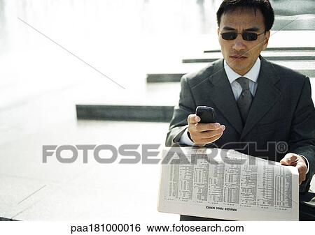 Stock Photograph - Businessman looking at cell phone, outdoors. Fotosearch