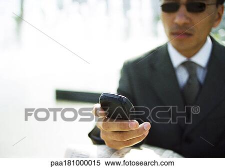Stock Photography - Businessman looking at cell phone, outdoors, close-up. Fotosearch