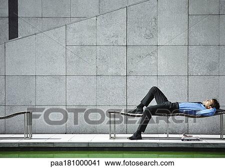 Businessman lying on bench outdoors View Large Photo Image Stock Image - Businessman lying on bench outdoors. Fotosearch
