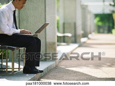 Businessman on bench with laptop computer View Large Photo Image Stock Photo - Businessman on bench with laptop computer. Fotosearch