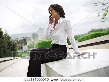 Businessman sitting outdoors, using cell phone View Large Photo Image Stock Image - Businessman sitting outdoors, using cell phone. Fotosearch