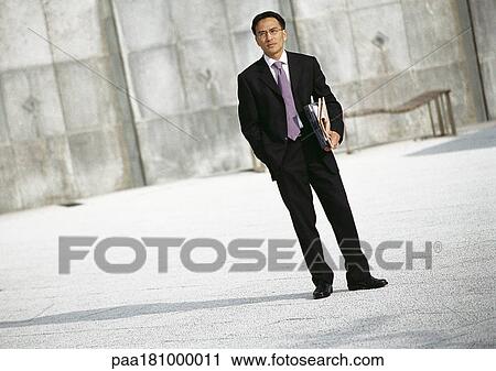 Businessman standing outdoors, portrait View Large Photo Image Stock Image - Businessman standing outdoors, portrait. Fotosearch