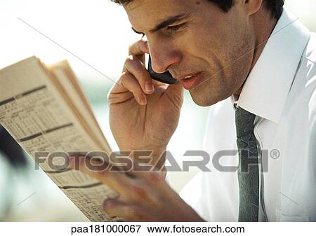 Businessman using cell phone and looking at newspaper, close-up, side view View Large Photo Image Stock Photo - Businessman using cell phone and looking at newspaper, close-up, side view. Fotosearch