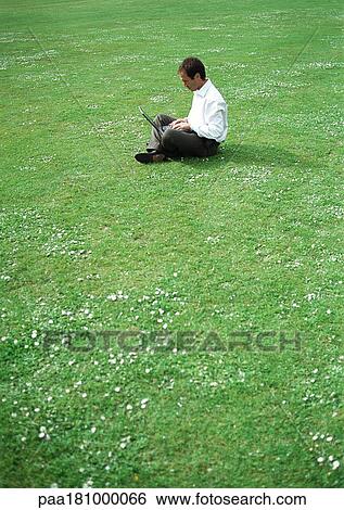 Stock Photograph - Businessman using laptop on grass . Fotosearch