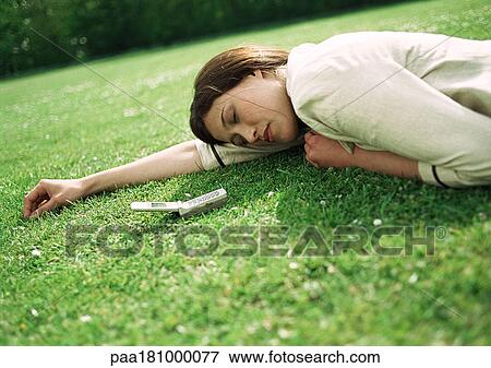 Stock Photo - Businesswoman lying on grass with cell phone near head. Fotosearch