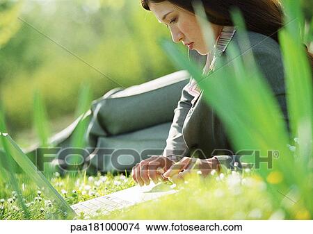 Businesswoman lying on grass with laptop computer View Large Photo Image Picture - Businesswoman lying on grass with laptop computer. Fotosearch