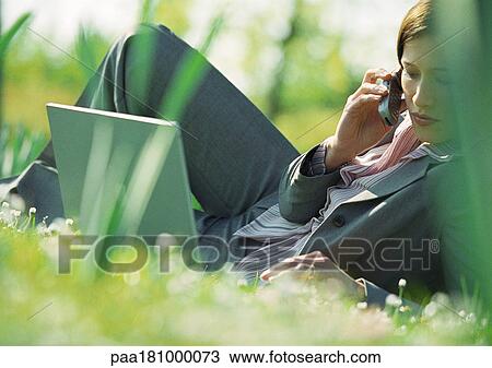 Businesswoman lying on grass with laptop and cell phone View Large Photo Image Stock Image - Businesswoman lying on grass with laptop and cell phone. Fotosearch