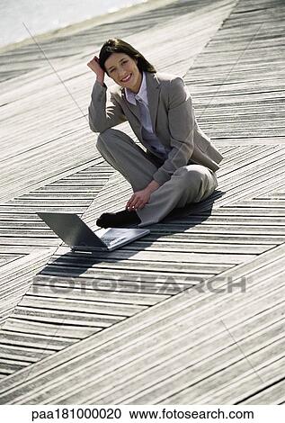 Businesswoman sitting on ground with laptop, outdoors View Large Photo Image Stock Image - Businesswoman sitting on ground with laptop, outdoors. Fotosearch