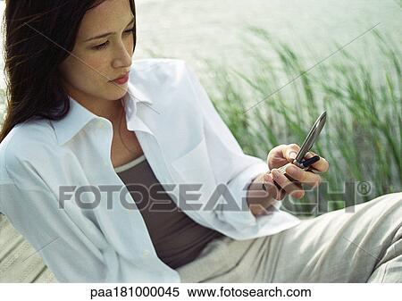 Businesswoman sitting outdoors, using cell phone View Large Photo Image Stock Photography - Businesswoman sitting outdoors, using cell phone. Fotosearch