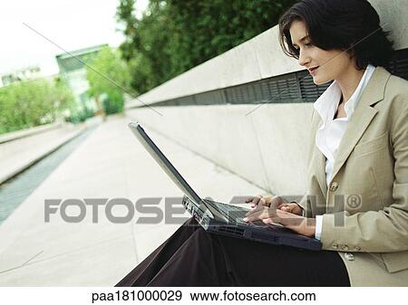 Businesswoman sitting with laptop computer outdoors View Large Photo Image Stock Photo - Businesswoman sitting with laptop computer outdoors. Fotosearch