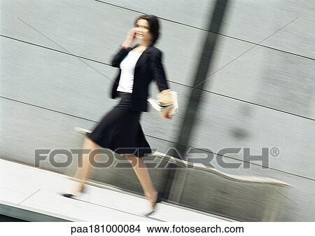 Businesswoman using cell phone and walking, blurred View Large Photo Image Picture - Businesswoman using cell phone and walking, blurred. Fotosearch