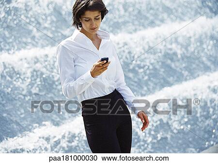 Businesswoman using cell phone in front of fountain View Large Photo Image Stock Image - Businesswoman using cell phone in front of fountain. Fotosearch