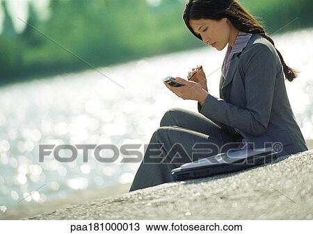 Businesswoman using hand held computer, outdoors View Large Photo Image Stock Image - Businesswoman using hand held computer, outdoors. Fotosearch