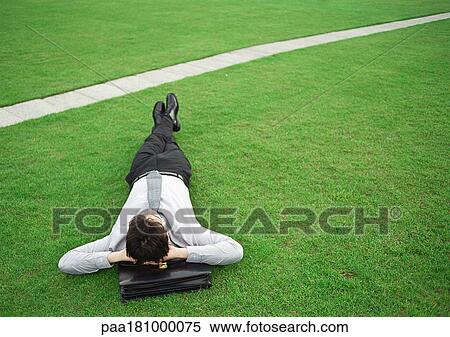 Man lying on grass, head on briefcase View Large Photo Image Stock Photography - Man lying on grass, head on briefcase. Fotosearch