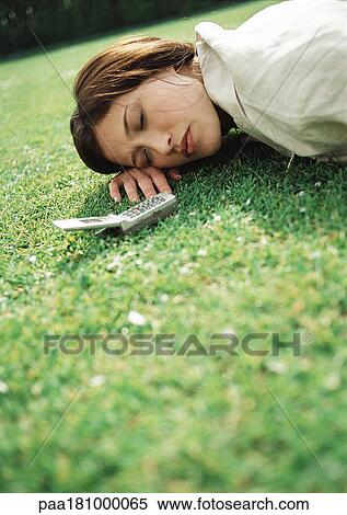 Woman lying on grass with cell phone near head, close-up View Large Photo Image Stock Photography - Woman lying on grass with cell phone near head, close-up. Fotosearch