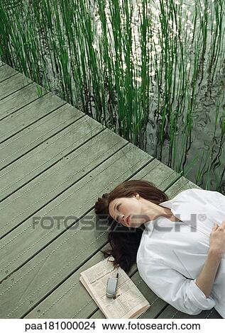 Woman resting on wood bridge, head and shoulders, high angle view View Large Photo Image Picture - Woman resting on wood bridge, head and shoulders, high angle view. Fotosearch