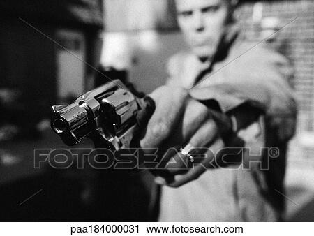 Stock Image - Man holding gun, close-up, b&w. Fotosearch