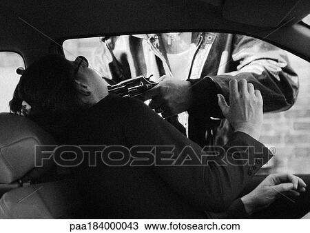 Stock Image - Man holding gun to woman's face through car window, b&w. Fotosearch