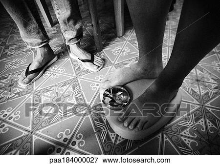 Stock Photo - People in bathroom, one person standing on scales, low section, b&w. Fotosearch