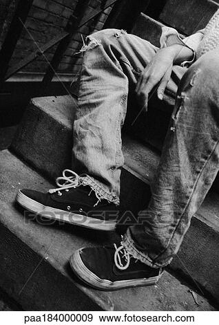 Stock Photo - Person sitting on stairs, low section, b&w. Fotosearch