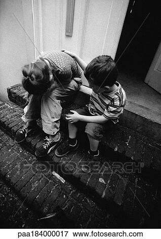 Stock Photo - Two children on stairs, one holding head in hands, b&w. Fotosearch