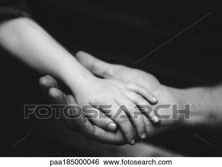 Stock Photograph - Adult's hand holding child's hand, close-up, b&w. Fotosearch