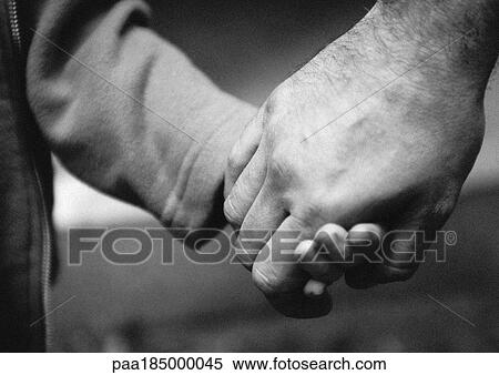 Stock Photography - Adult's hand holding child's hand, close-up, b&w. Fotosearch