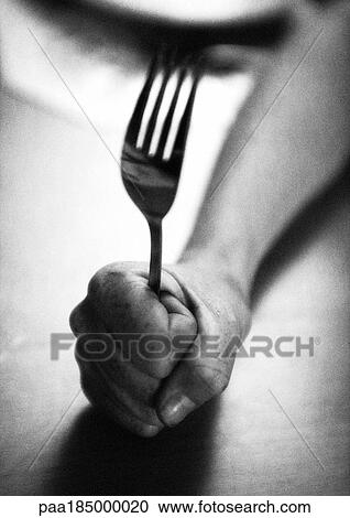 Stock Image - Hand holding fork, close-up, b&w. Fotosearch