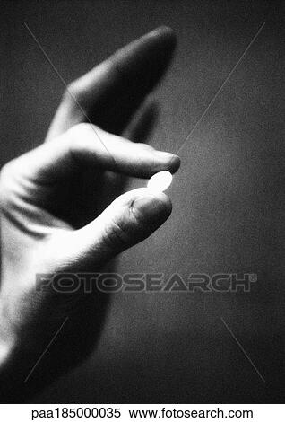 Stock Photography - Hand holding pill, close-up, b&w. Fotosearch