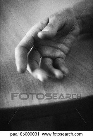 Stock Image - Hand on table, close-up, b&w. Fotosearch