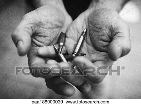 Stock Photo - Hands holding bullets, close-up, b&w. Fotosearch