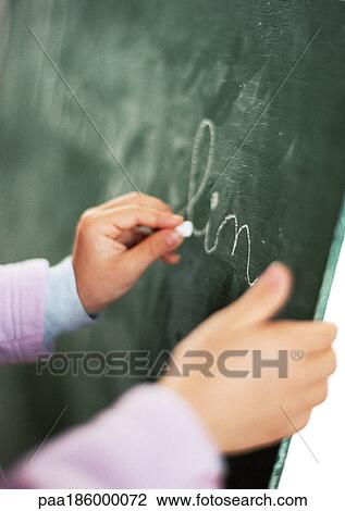 Stock Image - Child writing on chalkboard, close-up. Fotosearch