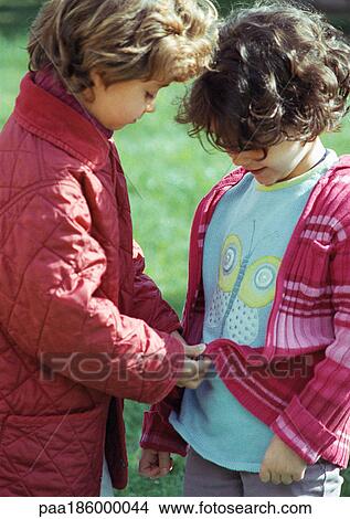 Child zipping friend's sweater, outdoors View Large Photo Image Picture - Child zipping friend's sweater, outdoors. Fotosearch