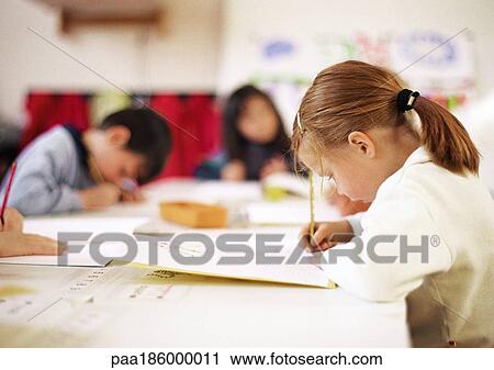Children sitting at table, writing View Large Photo Image Stock Image - Children sitting at table, writing. Fotosearch