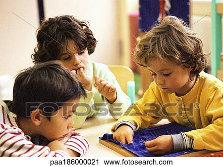 Three children sitting at table, one sewing View Large Photo Image Stock Image - Three children sitting at table, one sewing. Fotosearch