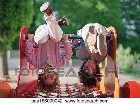 Two children hanging upside down on jungle gym View Large Photo Image Stock Image - Two children hanging upside down on jungle gym. Fotosearch