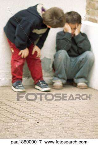 Stock Photo - Two children in corner, one holding head. Fotosearch