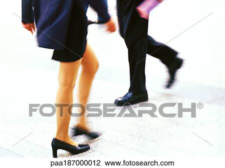 Stock Image - Businessman and businesswoman walking, low section. Fotosearch