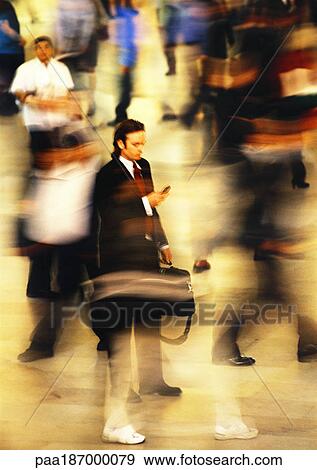 Businessman in blurred crowd, using cell phone, full length View Large Photo Image Stock Photo - Businessman in blurred crowd, using cell phone, full length. Fotosearch