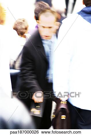 Stock Photograph - Businessman in crowd with briefcase in hand, blurred. Fotosearch