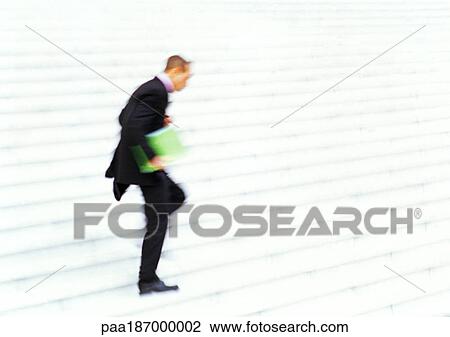 Stock Image - Businessman running down steps, side view, blurred motion. Fotosearch
