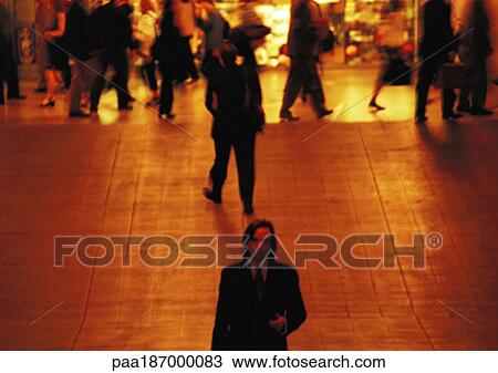 Stock Image - Businessman walking away from crowd, elevated view. Fotosearch