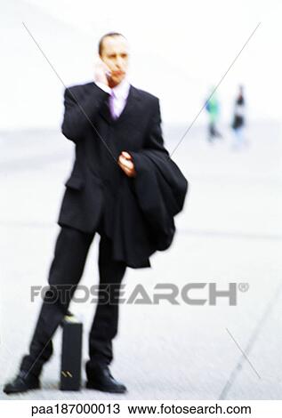 Businessman with briefcase in hand, using cell phone View Large Photo Image Stock Image - Businessman with briefcase in hand, using cell phone. Fotosearch
