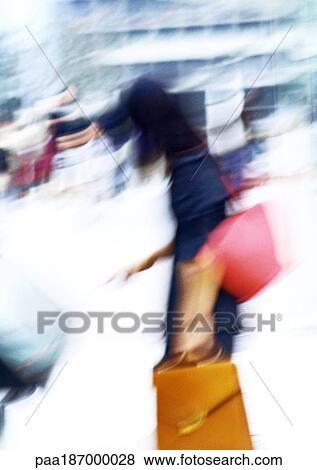 Stock Photo - Businesswoman carrying bags, blurred. Fotosearch