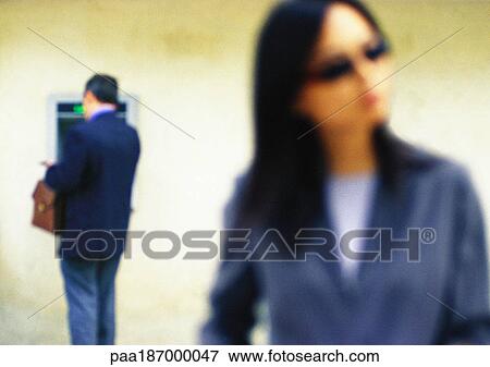 Businesswoman, head and shoulders, in foreground, man at atm in background, blurred View Large Photo Image Stock Photo - Businesswoman, head and shoulders, in foreground, man at atm in background, blurred. Fotosearch