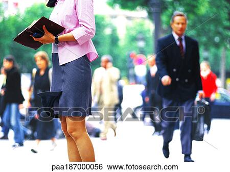 Stock Photograph - Businesswoman in crowd, holding open agenda, mid section. Fotosearch