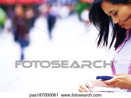 Businesswoman looking at cell phone, side view, close-up, off center View Large Photo Image Stock Image - Businesswoman looking at cell phone, side view, close-up, off center. Fotosearch