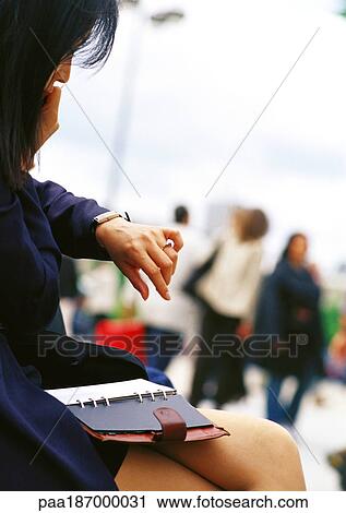 Businesswoman looking at watch, agenda on lap View Large Photo Image Stock Image - Businesswoman looking at watch, agenda on lap. Fotosearch